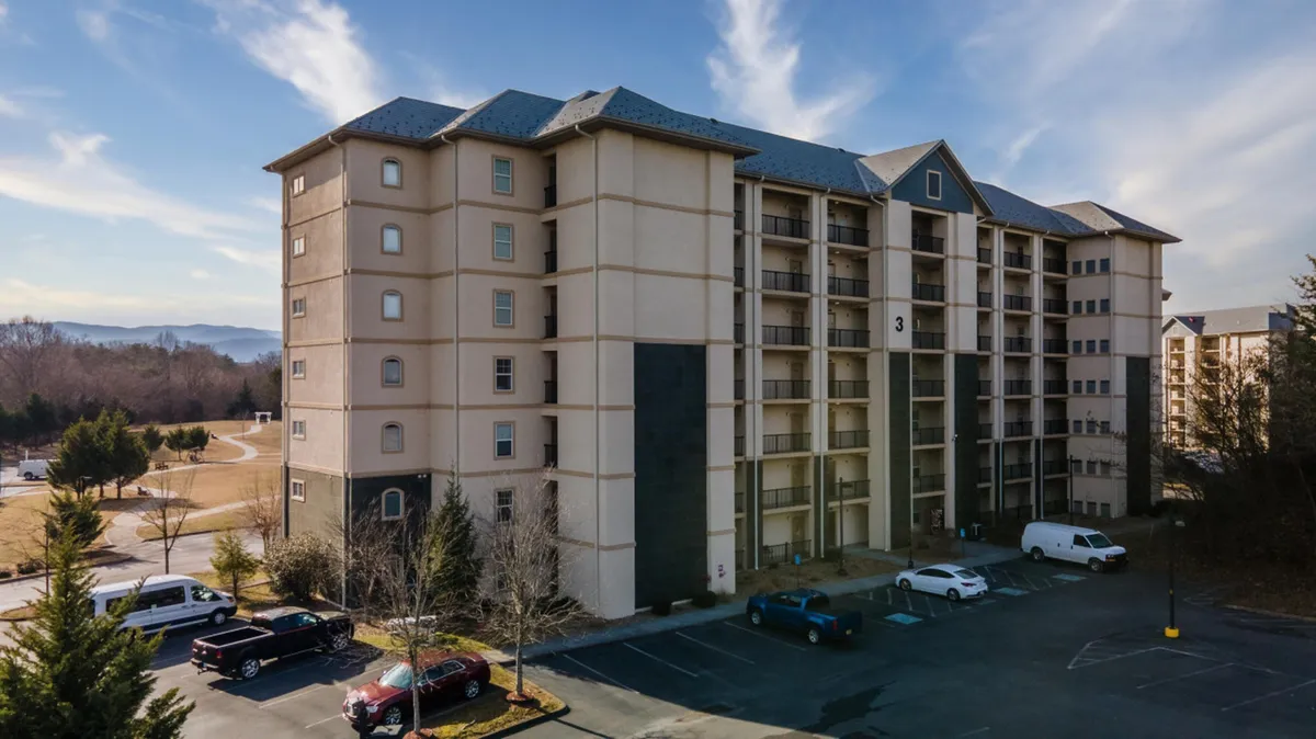A multi-story condo building with ample parking and gentle landscaping sets a welcoming tone. The open walkways, accessible entry points, and elevator access are implied through the building's design, demonstrating the resort's focus on convenience and mobility.
