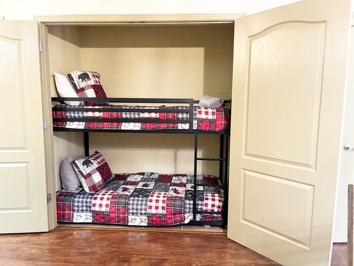 A dedicated bunk bed nook with plaid bedding and decorative pillows, designed to be fun and comfortable for children. The intimate space offers a playful yet practical sleeping solution for younger guests.