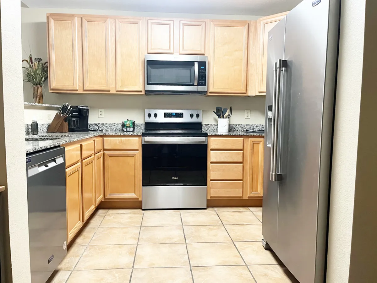 A welcoming kitchen featuring a stainless steel refrigerator, granite countertop, and wooden cabinetry, complemented by modern appliances. The space is bright and ideal for meal prep, cooking, and hosting family gatherings.